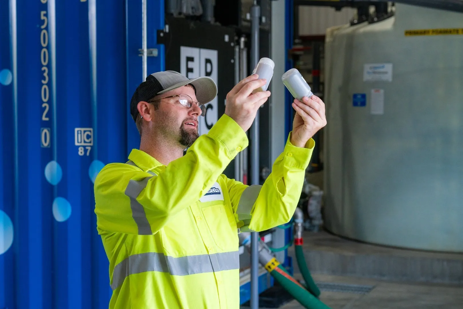 A worker holding up two sample containers and comparing them
