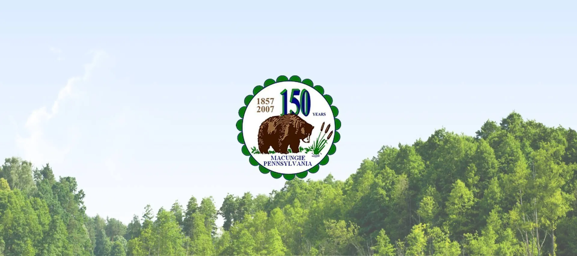 Macungie, Pennsylvania anniversary logo centered above a green forested landscape beneath a pale blue sky.