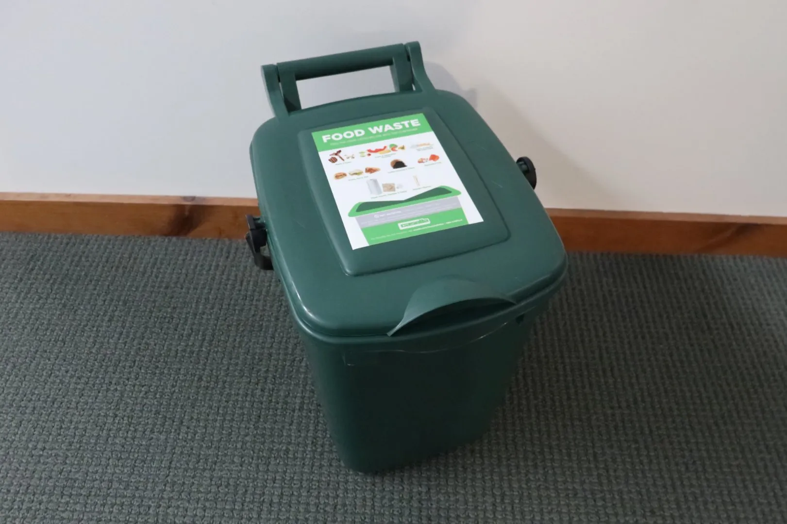 Green food waste bin with a labeled lid showing acceptable compostable items