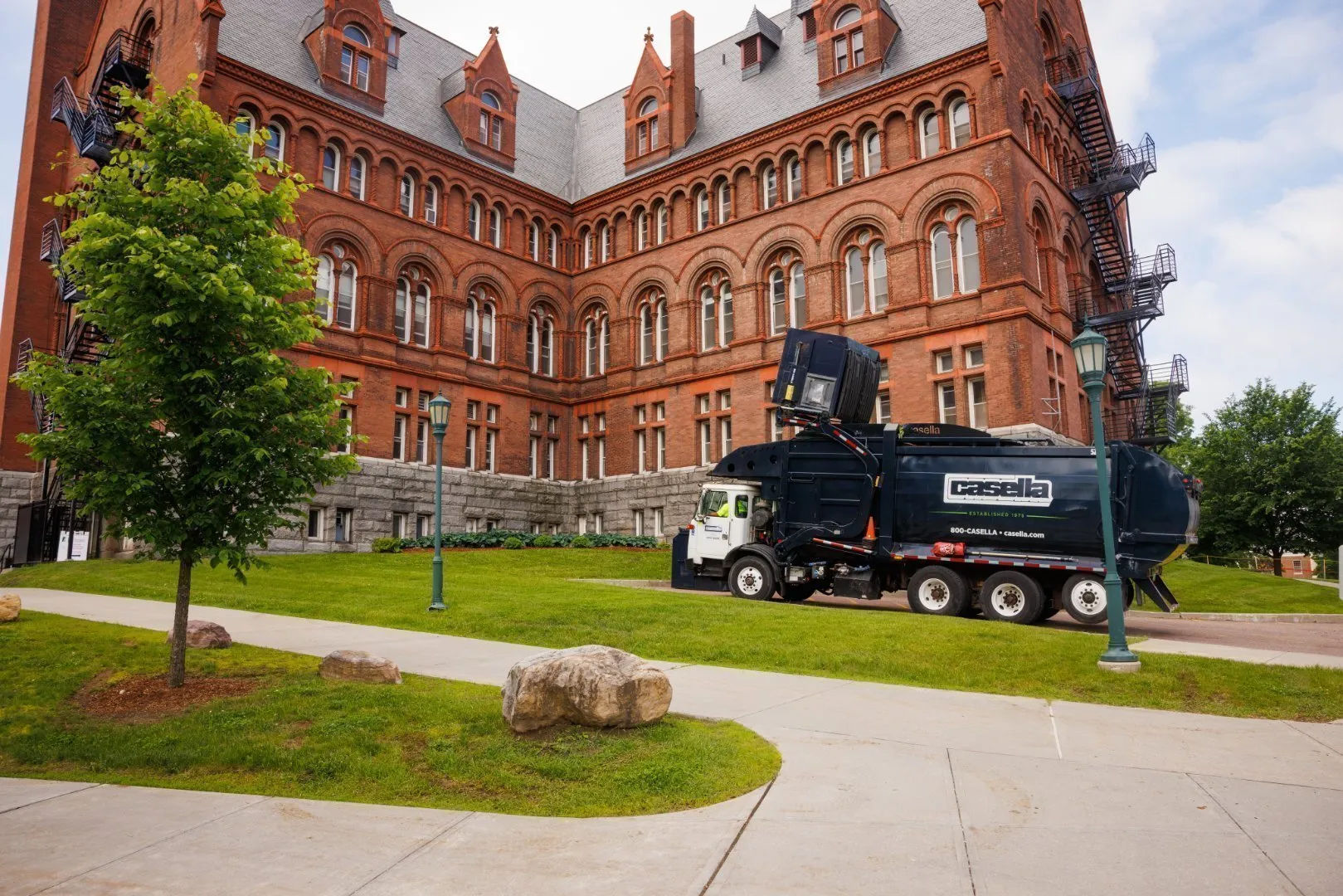 Red brick building with garbage truck on campus lawn.