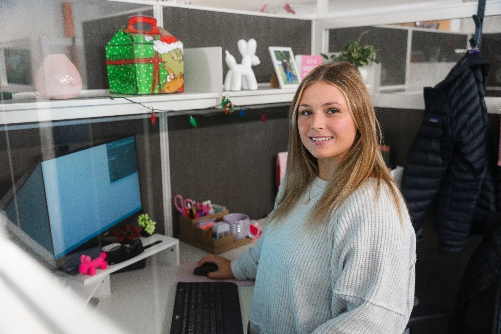 Accounts Payable Specialist wearing a light sweater is seated at a desk working on a computer with a keyboard and mouse.
