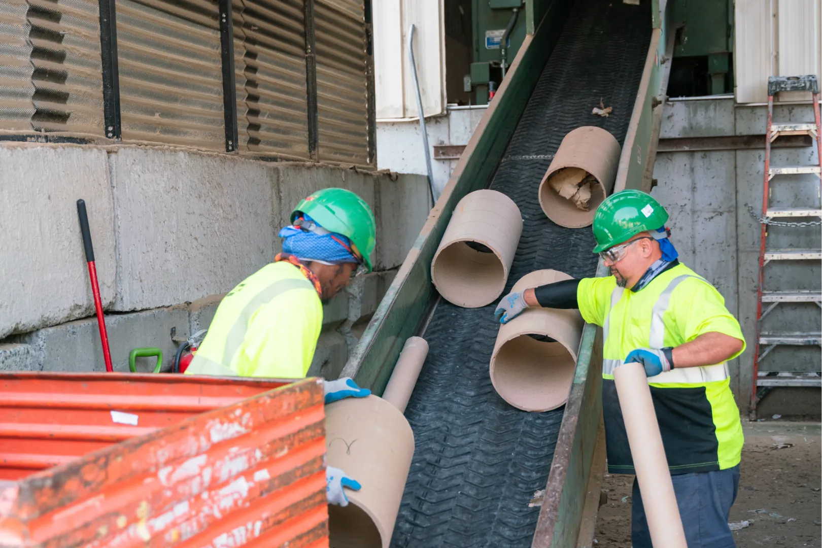 Two Casella workers working with recycling waste on a conveyor belt.