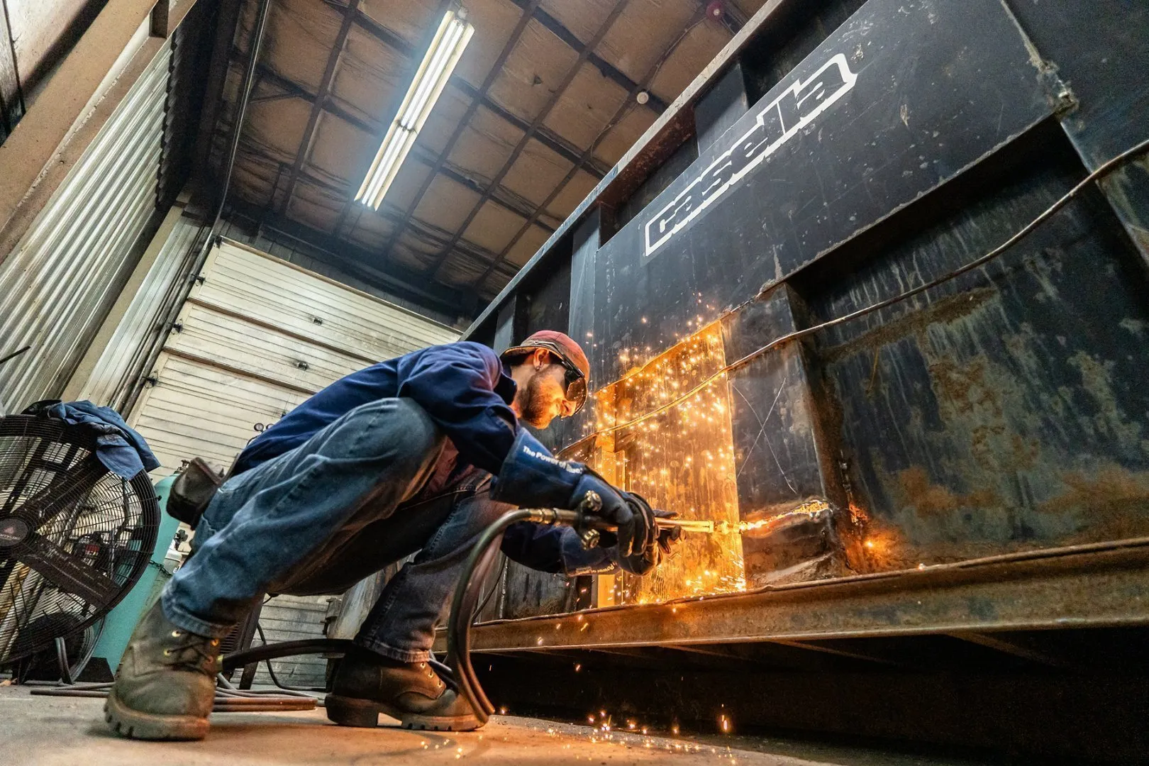 A worker welding a dumpster.