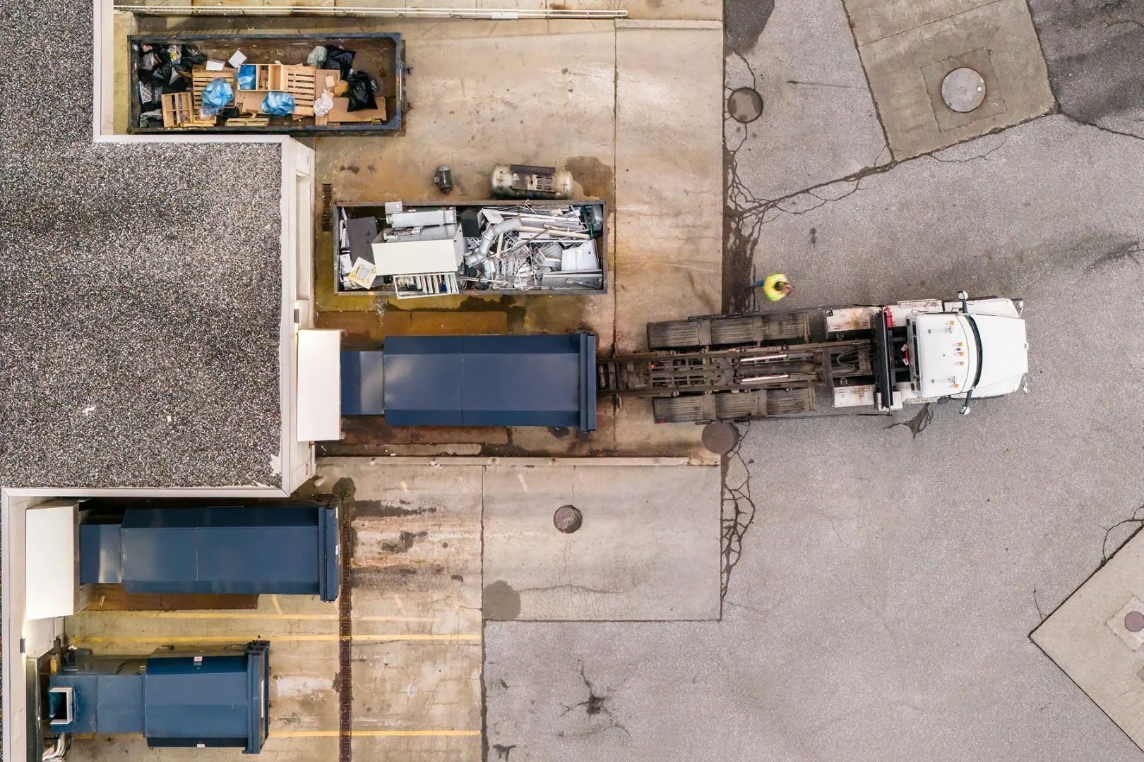 Casella commercial container pickup behind a business, showing driver, truck, and multiple waste and recycling containers.
