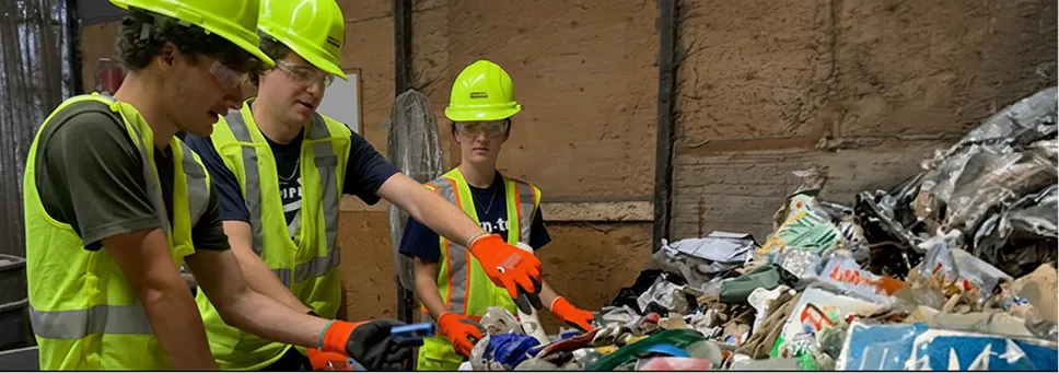Workers in safety gear sorting mixed waste materials at a recycling facility, demonstrating Casella’s commitment to responsible resource management.
