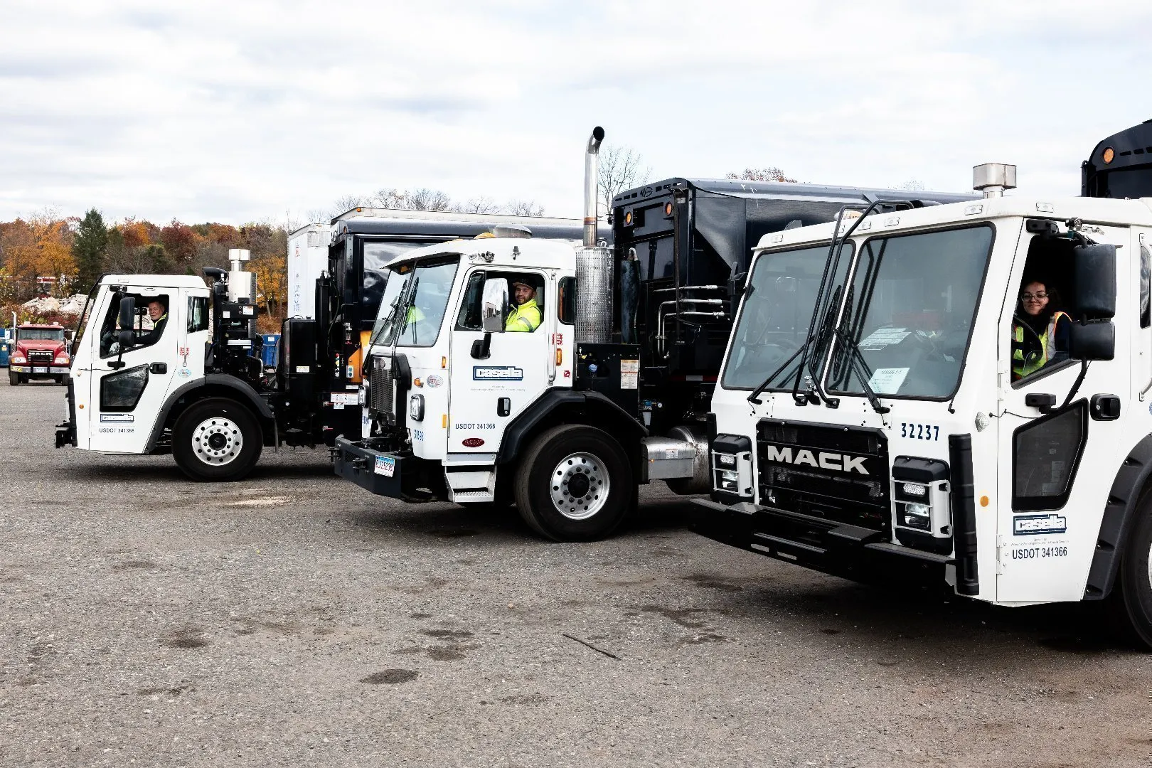 Three Casella garbage trucks parked side by side in an outdoor lot.