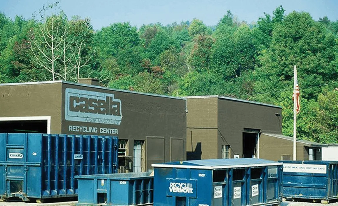 Casella Recycling Center featuring blue containers labeled for material sorting, located in a wooded area and supporting Vermont’s environmental sustainability efforts.