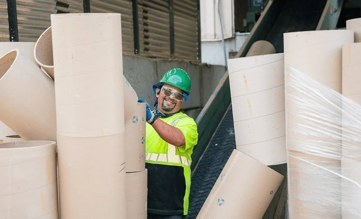 Casella technician loading cores onto a conveyor system at an industrial recycling facility.