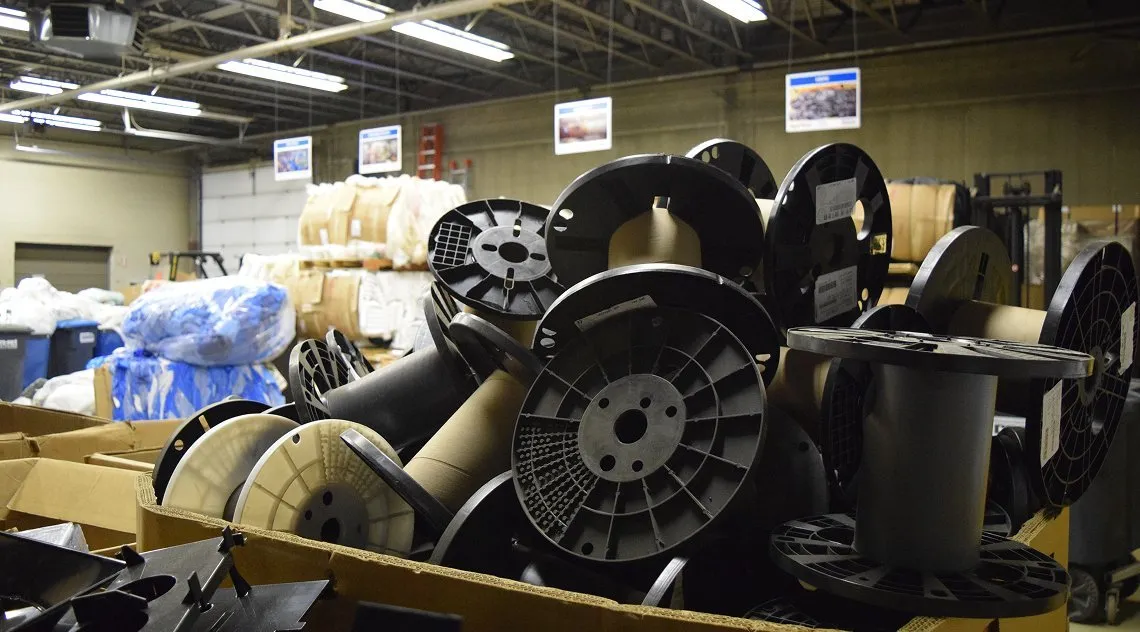Warehouse with cardboard boxes filled with empty plastic spools and industrial materials, highlighting Casella’s recycling and sustainable materials recovery services for commercial operations.